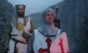 Movie still from “Monty Python and the Holy Grail” (1975), directed by Terry Gilliam – A group of people dressed in medieval costumes; Medium shot, Low angle
