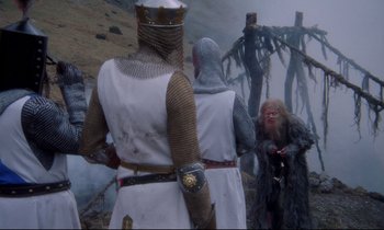 Movie still from “Monty Python and the Holy Grail” (1975), directed by Terry Gilliam – A group of people dressed in medieval clothing; Wide shot, Over the shoulder angle