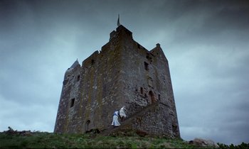 Movie still from “Monty Python and the Holy Grail” (1975), directed by Terry Gilliam – Two people standing on the top of a hill near an old castle; Extreme Wide shot, Low angle