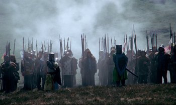 Movie still from “Monty Python and the Holy Grail” (1975), directed by Terry Gilliam – A group of people standing in a field with flags; Wide shot, High angle