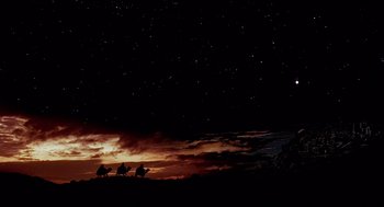 Movie still from “Life of Brian” (1979), directed by Terry Jones – A group of people riding on the back of a camel; Extreme Wide shot, Low angle