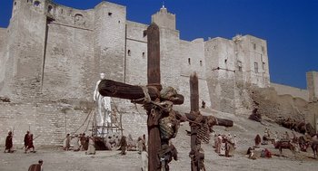 Movie still from “Life of Brian” (1979), directed by Terry Jones – A group of people standing next to a wooden cross; Extreme Wide shot, Low angle