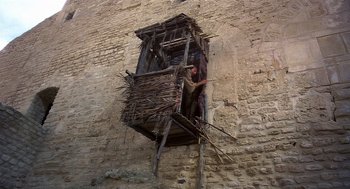 Movie still from “Life of Brian” (1979), directed by Terry Jones – A man standing on a ladder next to a window; Wide shot, Low angle
