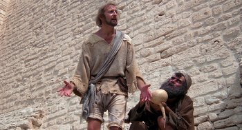 Movie still from “Life of Brian” (1979), directed by Terry Jones – A man and a bearded man are standing next to a brick wall; Medium shot, Low angle