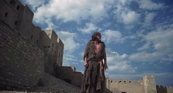 Movie still from “Life of Brian” (1979), directed by Terry Jones – A man dressed as a pirate standing in front of a castle; Wide shot, Low angle