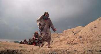 Movie still from “Life of Brian” (1979), directed by Terry Jones – A group of men walking across a dirt field; Wide shot, Low angle
