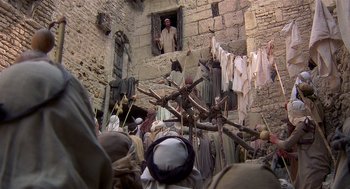 Movie still from “Life of Brian” (1979), directed by Terry Jones – A group of people standing around a building with clothes hanging; Wide shot, Low angle