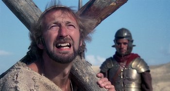 Movie still from “Life of Brian” (1979), directed by Terry Jones – A man holding a wooden cross while another man stands next to him; Close Up shot, Low angle