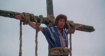 Movie still from “Life of Brian” (1979), directed by Terry Jones – A man is tied to a wooden cross; Medium shot, Low angle