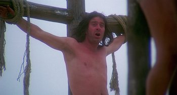 Movie still from “Life of Brian” (1979), directed by Terry Jones – A shirtless man hanging from a cross with a rope; Medium shot, Low angle