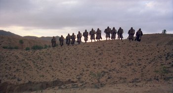 Movie still from “Life of Brian” (1979), directed by Terry Jones – A group of people walking up a steep hill; Extreme Wide shot, Low angle