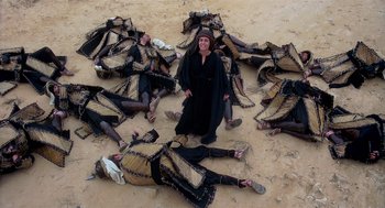 Movie still from “Life of Brian” (1979), directed by Terry Jones – A group of people laying on the ground with one woman standing in front of them; Wide shot, High angle
