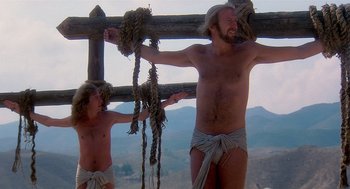 Movie still from “Life of Brian” (1979), directed by Terry Jones – A man and a boy hanging from a wooden fence; Medium shot, Low angle