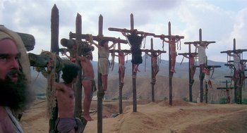 Movie still from “Life of Brian” (1979), directed by Terry Jones – A group of men hanging from wooden crosses on top of a hill; Extreme Wide shot, Low angle