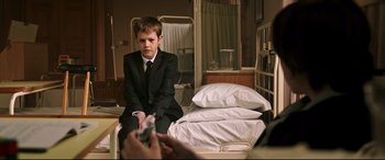 Movie still from “Morbius” (2022), directed by Daniel Espinosa – A boy in a suit sitting on a hospital bed; Medium shot, Over the shoulder angle