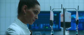 Movie still from “Morbius” (2022), directed by Daniel Espinosa – A woman in a white shirt is standing in front of an infusion pump; Close Up shot, Over the shoulder angle