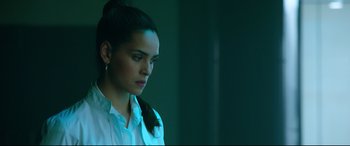 Movie still from “Morbius” (2022), directed by Daniel Espinosa – A woman with a ponytail is standing in a dark room; Close Up shot, Over the shoulder angle
