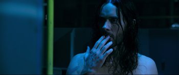 Movie still from “Morbius” (2022), directed by Daniel Espinosa – A man with long black hair is eating something off his hand; Close Up shot, High angle