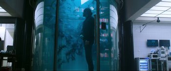 Movie still from “Morbius” (2022), directed by Daniel Espinosa – A man standing in front of an aquarium in a room; Wide shot, Low angle