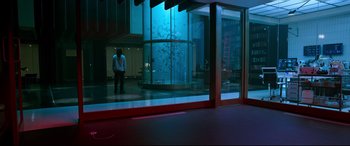 Movie still from “Morbius” (2022), directed by Daniel Espinosa – A man standing in front of an aquarium in a building; Wide shot, Over the shoulder angle