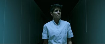 Movie still from “Morbius” (2022), directed by Daniel Espinosa – A man in a white shirt is standing in a dark room; Medium shot, Low angle