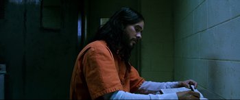 Movie still from “Morbius” (2022), directed by Daniel Espinosa – A man in an orange shirt sitting at a table; Medium shot, High angle