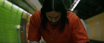Movie still from “Morbius” (2022), directed by Daniel Espinosa – A man with long black hair wearing an orange shirt; Medium shot, High angle