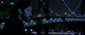 Movie still from “Morbius” (2022), directed by Daniel Espinosa – A person looking at a bridge at night; Close Up shot, Over the shoulder angle