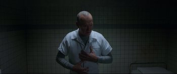 Movie still from “Morbius” (2022), directed by Daniel Espinosa – An older man is holding his hands over his chest; Medium shot, High angle