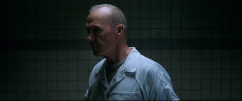 Movie still from “Morbius” (2022), directed by Daniel Espinosa – An older man in a white shirt is standing in a dark room; Close Up shot, Over the shoulder angle