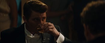 Movie still from “Mudbound” (2017), directed by Dee Rees – A man in a tuxedo drinking from a wine glass; Close Up shot, Over the shoulder angle