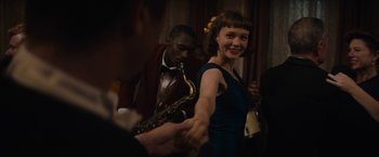 Movie still from “Mudbound” (2017), directed by Dee Rees – A woman in a blue dress is holding a saxophone; Medium shot, Over the shoulder angle