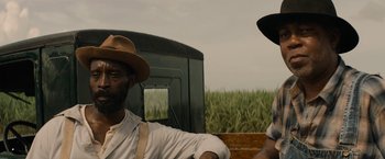 Movie still from “Mudbound” (2017), directed by Dee Rees – Two men are sitting next to each other in front of a field; Close Up shot, Over the shoulder angle