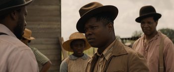 Movie still from “Mudbound” (2017), directed by Dee Rees – A man wearing a hat standing next to another man; Close Up shot, Over the shoulder angle