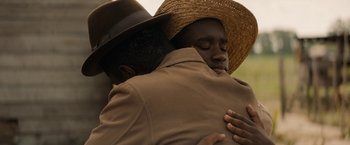 Movie still from “Mudbound” (2017), directed by Dee Rees – Two men hugging each other wearing hats and jackets; Close Up shot, Over the shoulder angle