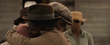 Movie still from “Mudbound” (2017), directed by Dee Rees – Two men are hugging each other in front of another man wearing a hat; Close Up shot, Over the shoulder angle