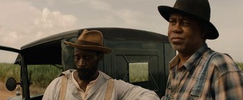 Movie still from “Mudbound” (2017), directed by Dee Rees – Two men are standing next to each other in front of a truck; Close Up shot, Over the shoulder angle
