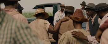 Movie still from “Mudbound” (2017), directed by Dee Rees – A group of people standing next to each other on a road; Medium shot, Over the shoulder angle