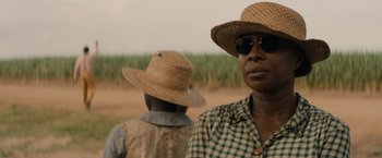 Movie still from “Mudbound” (2017), directed by Dee Rees – Two people wearing straw hats and sunglasses in a field; Close Up shot, Over the shoulder angle