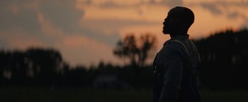 Movie still from “Mudbound” (2017), directed by Dee Rees – A man standing in a field at sunset; Medium shot, Low angle