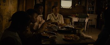 Movie still from “Mudbound” (2017), directed by Dee Rees – Three people are sitting at a table with plates of food in front of them; Medium shot, High angle