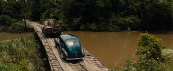 Movie still from “Mudbound” (2017), directed by Dee Rees – An old car is parked on a wooden bridge; Extreme Wide shot, High angle