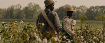 Movie still from “Mudbound” (2017), directed by Dee Rees – A couple of men standing next to each other in a field; Medium shot, High angle