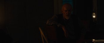 Movie still from “Mudbound” (2017), directed by Dee Rees – An older man sitting in a chair in a dark room; Medium shot, Over the shoulder angle
