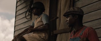 Movie still from “Mudbound” (2017), directed by Dee Rees – Two men sitting next to each other in front of a wooden wall; Medium shot, Over the shoulder angle