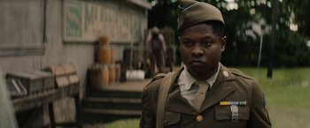 Movie still from “Mudbound” (2017), directed by Dee Rees – A man in a military uniform standing in front of a building; Close Up shot, Over the shoulder angle
