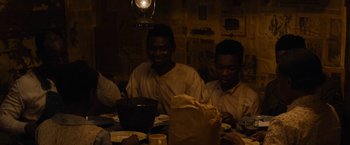 Movie still from “Mudbound” (2017), directed by Dee Rees – A group of people sitting at a table with food on it; Medium shot, High angle
