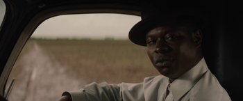 Movie still from “Mudbound” (2017), directed by Dee Rees – A man in a hat sitting in the driver's seat of a car; Close Up shot, Over the shoulder angle