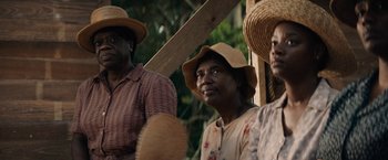 Movie still from “Mudbound” (2017), directed by Dee Rees – A group of people wearing straw hats and holding wooden sticks; Close Up shot, Over the shoulder angle
