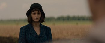Movie still from “Mudbound” (2017), directed by Dee Rees – A woman wearing a hat standing in front of a field; Close Up shot, Over the shoulder angle